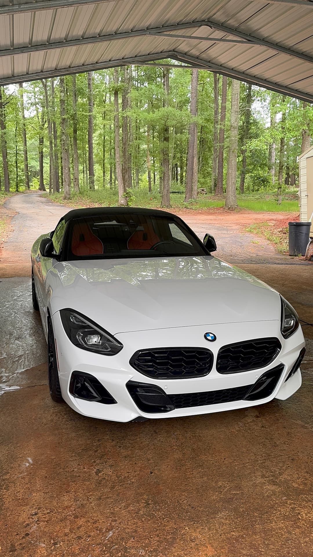 White BMW Z4 convertible rinsed and finished under a carport